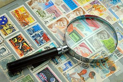 A magnifying glass on top of old stamps.