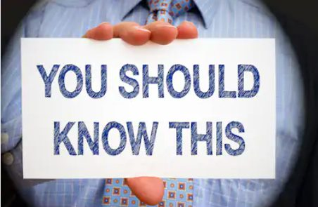 A man wearing a tie that's holding a white card that reads, "you should know this."