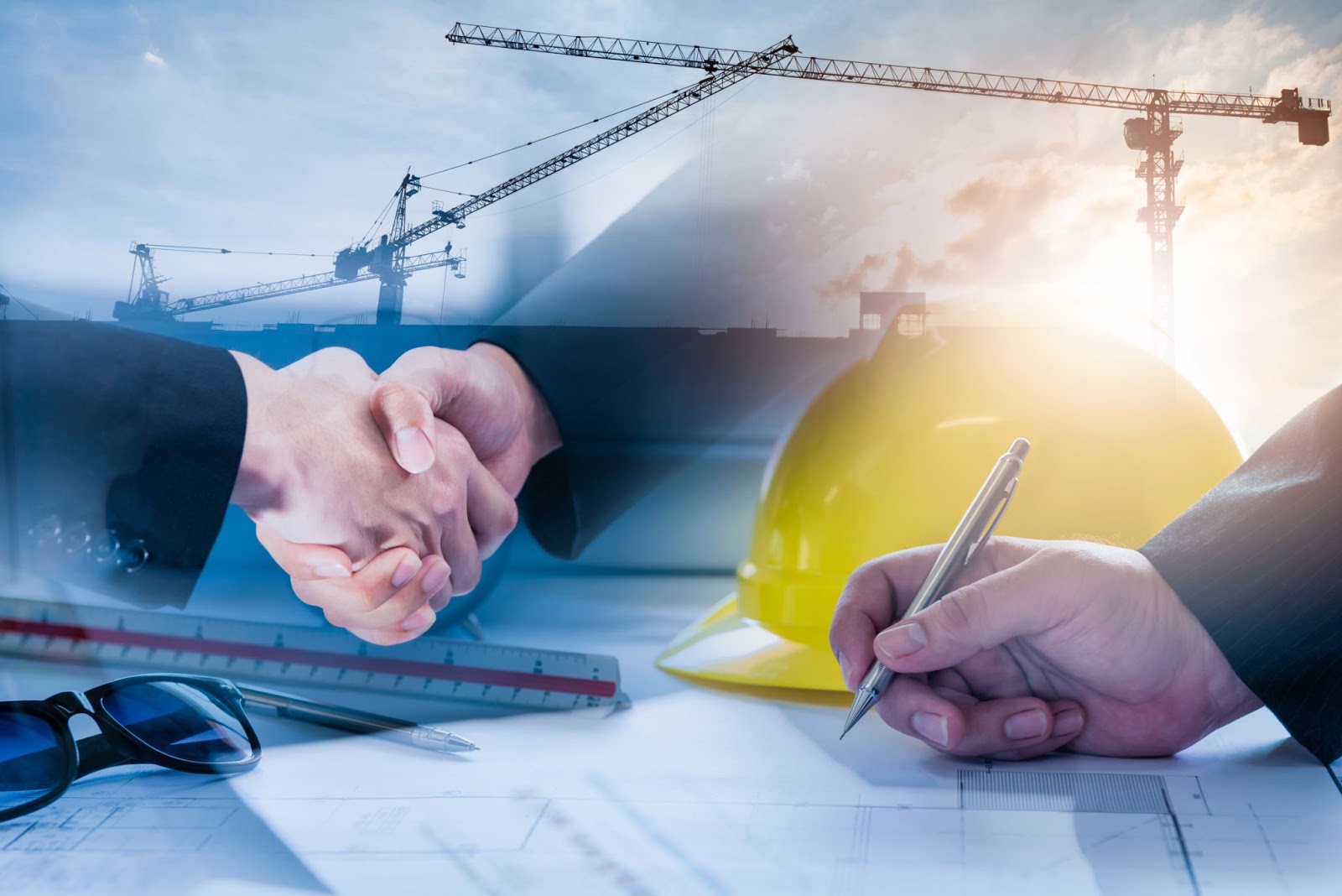 Two people shaking hands while another person signs a contact. There construction equipment in the background.