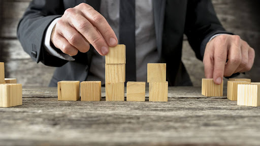 A man stacks blocks as a metaphor for building a business.